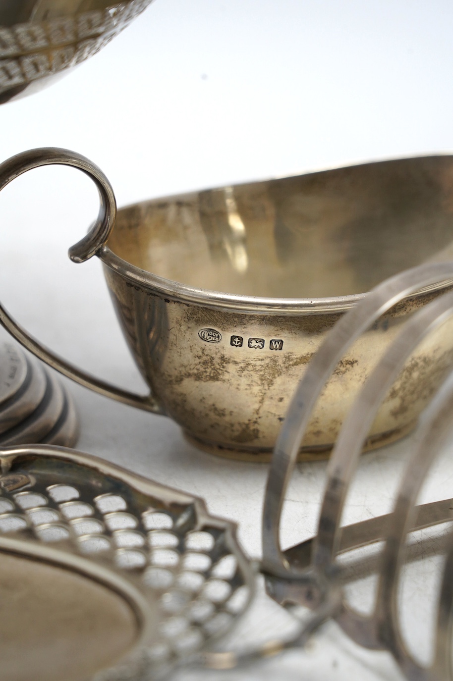 A pair of George VI silver five bar toast racks, Charles Boyton & Sons Ltd, London, 1937, 79mm, together with a small silver sauce boat, a silver two handled shallow dish and a pierced silver tazze, 15oz. Condition - fai